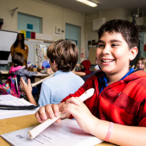 Boy holding recorder and smiling in classroom