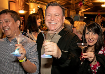 Three Members Raise Their Glasses to the Camera During a Reception in the Warner Grand Lobby