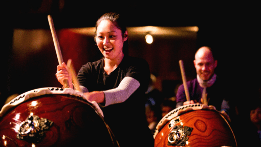 People playing taiko drums while smiling