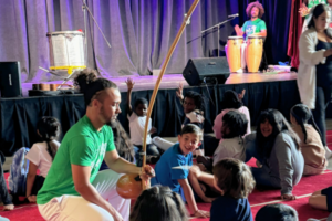 A member of Ballet Folclórico do Brasil shows a berimbau to a Meet the Music student