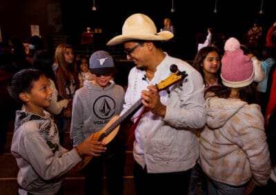 Roots of Music Program Field Trip Concert, a musician shows his guitar to a student