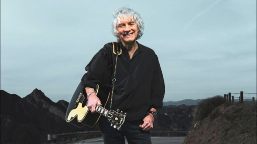 Albert Lee standing in the middle of the road with his guitar